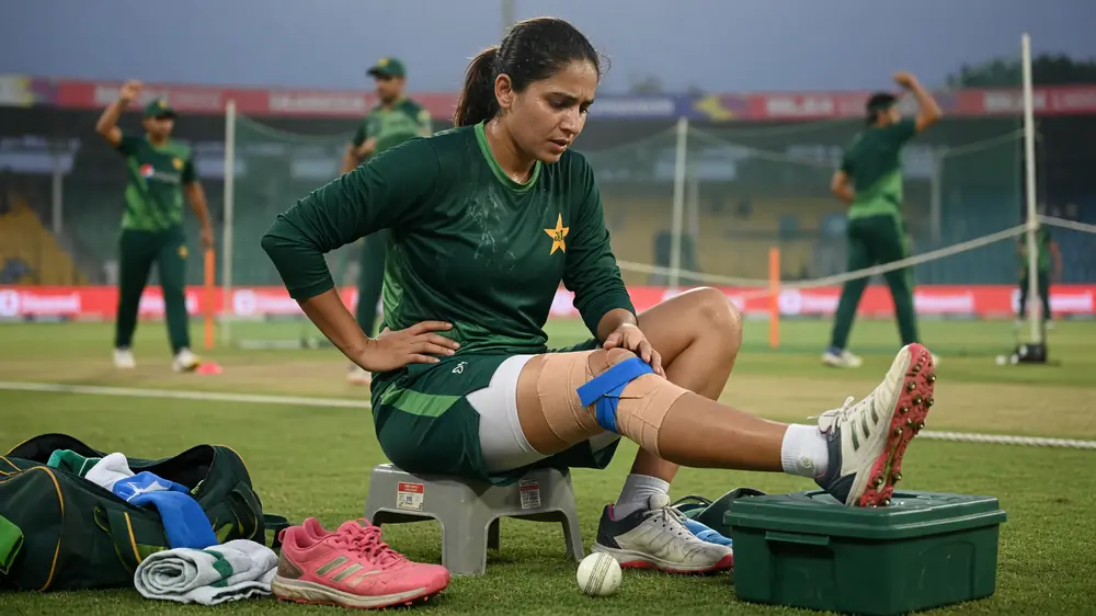 Women's cricket bowler in delivery stride under stadium lights during a T20 contest